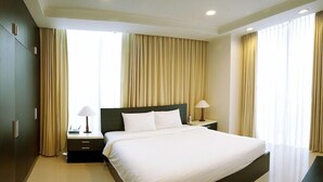 Een hotelkamer met een groot bed, twee nachtkastjes, een kledingkast en een nachtkastje.