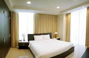 Een hotelkamer met een groot bed, twee nachtkastjes, een kledingkast en een nachtkastje.