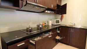 Een moderne keuken met donkerhouten kasten, een zwart aanrecht, een roestvrijstalen afzuigkap, een magnetron en een spoelbak.