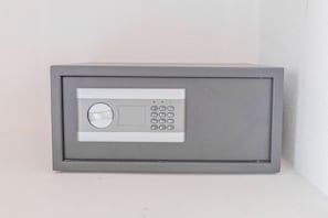 Een grijze kluis met een keypad en een ronde schijf, waarschijnlijk voor beveiliging.