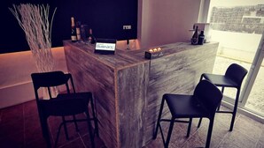 A modern bar area with a marble counter, two black bar stools, and a large window offering a view of the outside. - Hostal Balearic (Sant Antoni de Portmany)