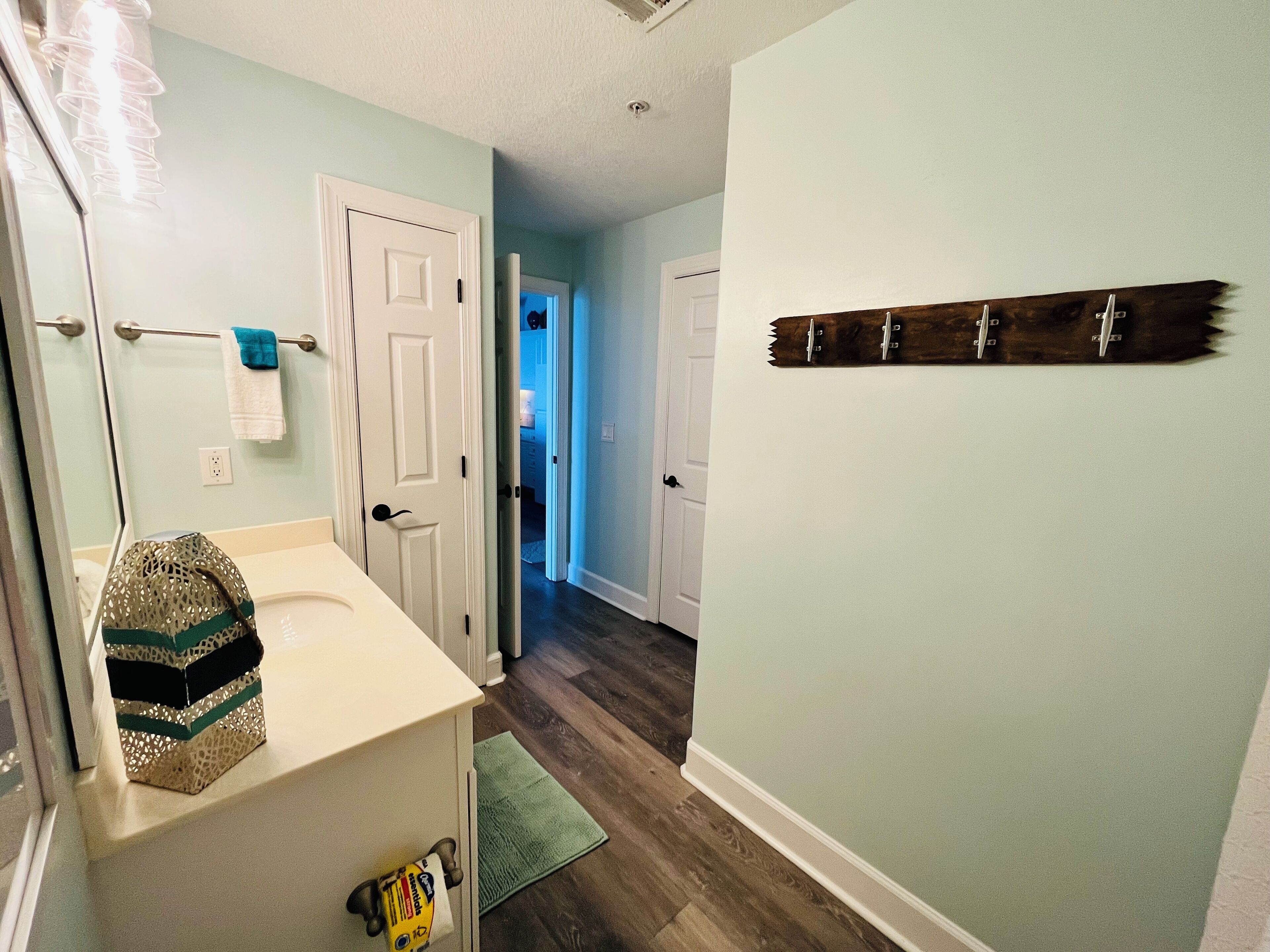 A bathroom with a white sink, a towel rack, and a decorative item on the wall.