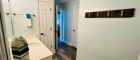 A bathroom with a white sink, a towel rack, and a decorative item on the wall.