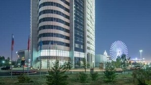 A modern hotel with a curved facade, multiple floors, and a prominent flagpole.