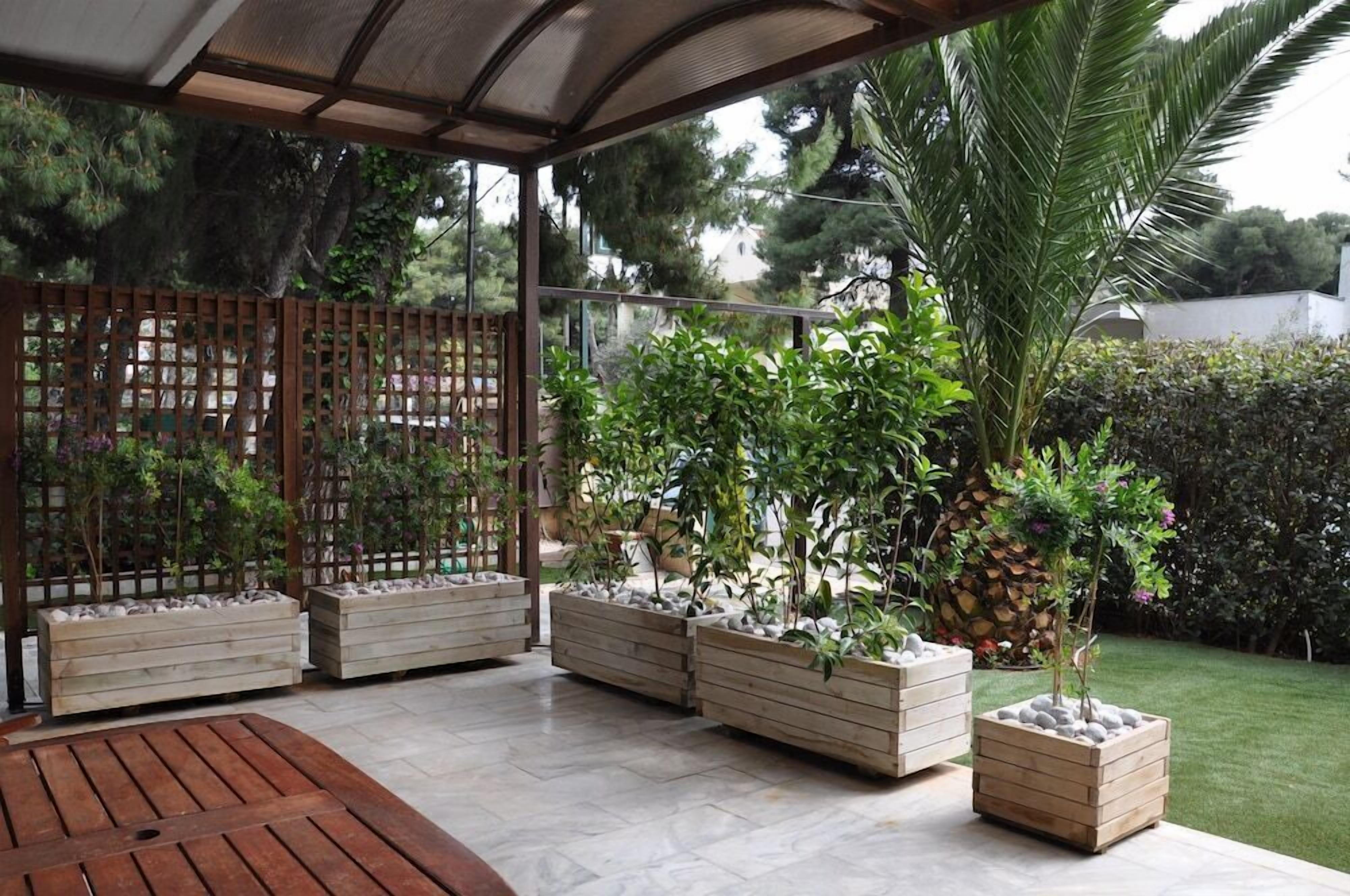 A covered outdoor seating area with wooden planters and a palm tree.