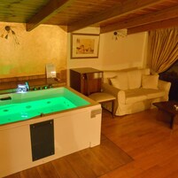 Una habitación con techo de madera, sofá color beige, una pequeña mesa y una mesa de billar con iluminación verde.