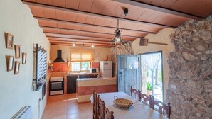 A spacious kitchen with a stone wall, wooden ceiling, and a dining area with a table and chairs. - Antigua Casa Rufo Pozo Alcón by Ruralidays (Jaén)