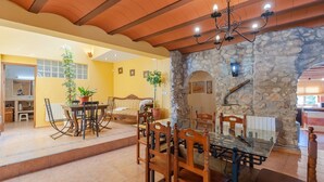 A dining area with a stone wall, wooden ceiling, and a chandelier. There is a table with chairs and a potted plant. - Antigua Casa Rufo Pozo Alcón by Ruralidays (Jaén)