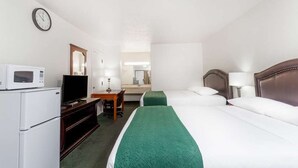 Una habitación de hotel con una cama, un escritorio con silla, un televisor, un microondas y un reloj en la pared.
