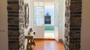 Passadís de parets de pedra que condueix a una porta amb vista a una barbacoa a l'exterior.