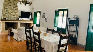 Una zona de menjador amb una llar de pedra, televisió i taula de dinar preparada per a sis.