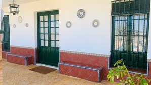 Edifici amb una porta verda, una banca i plats decoratius a la paret.