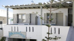 A building with a sign reading "Alexandras rooms" and a pergola with a satellite dish.