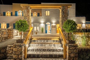 A modern building with a stone facade, a wooden staircase, and a blue door. - Marianna Hotel (Santorini)