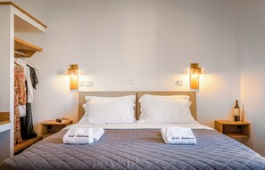 Ein Hotelzimmer mit Bett, zwei Nachttischen, einem Kleiderschrank und Wandleuchten.
