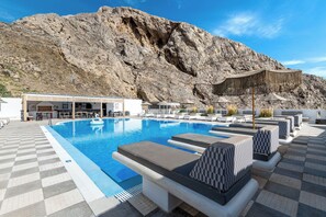 Un espace piscine avec des chaises longues, un bar et une vue imprenable sur les montagnes.