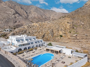A resort with a swimming pool, outdoor seating, and a view of rocky mountains. - Marianna Hotel (Santorini)