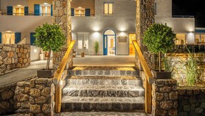 A modern building with a stone facade, a wooden staircase, and a blue door. - Marianna Hotel (Santorini)