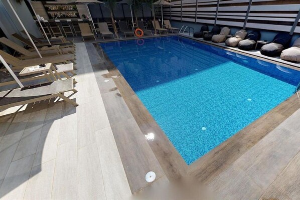 A swimming pool with lounge chairs and a sunbed area.