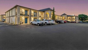 Un motel con varios pisos, un estacionamiento y varios vehículos estacionados.