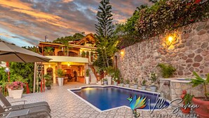 Una villa con piscina, muros de piedra y zona de estar al aire libre.