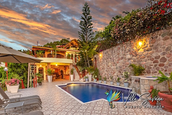 Eine Villa mit Swimmingpool, Steinmauern und Sitzgelegenheit im Freien.