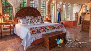 Un dormitorio con una cama grande, múltiples ventanas y un aparador de madera.