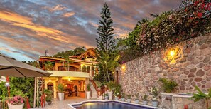 A villa with a swimming pool, stone walls, and outdoor seating.