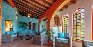 A spacious patio area with wicker furniture, tiled flooring, and large windows with arched tops.