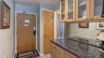 A kitchen with wooden cabinets, granite countertops, and a door with a doormat.