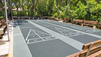 Una cancha de shuffleboard con áreas de puntuación numeradas y un espacio con bancos alrededor.