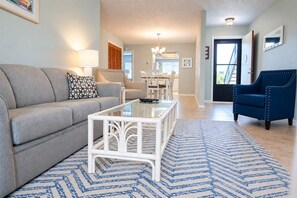 Un salon avec un canapé, une table basse et un tapis bleu à motifs.