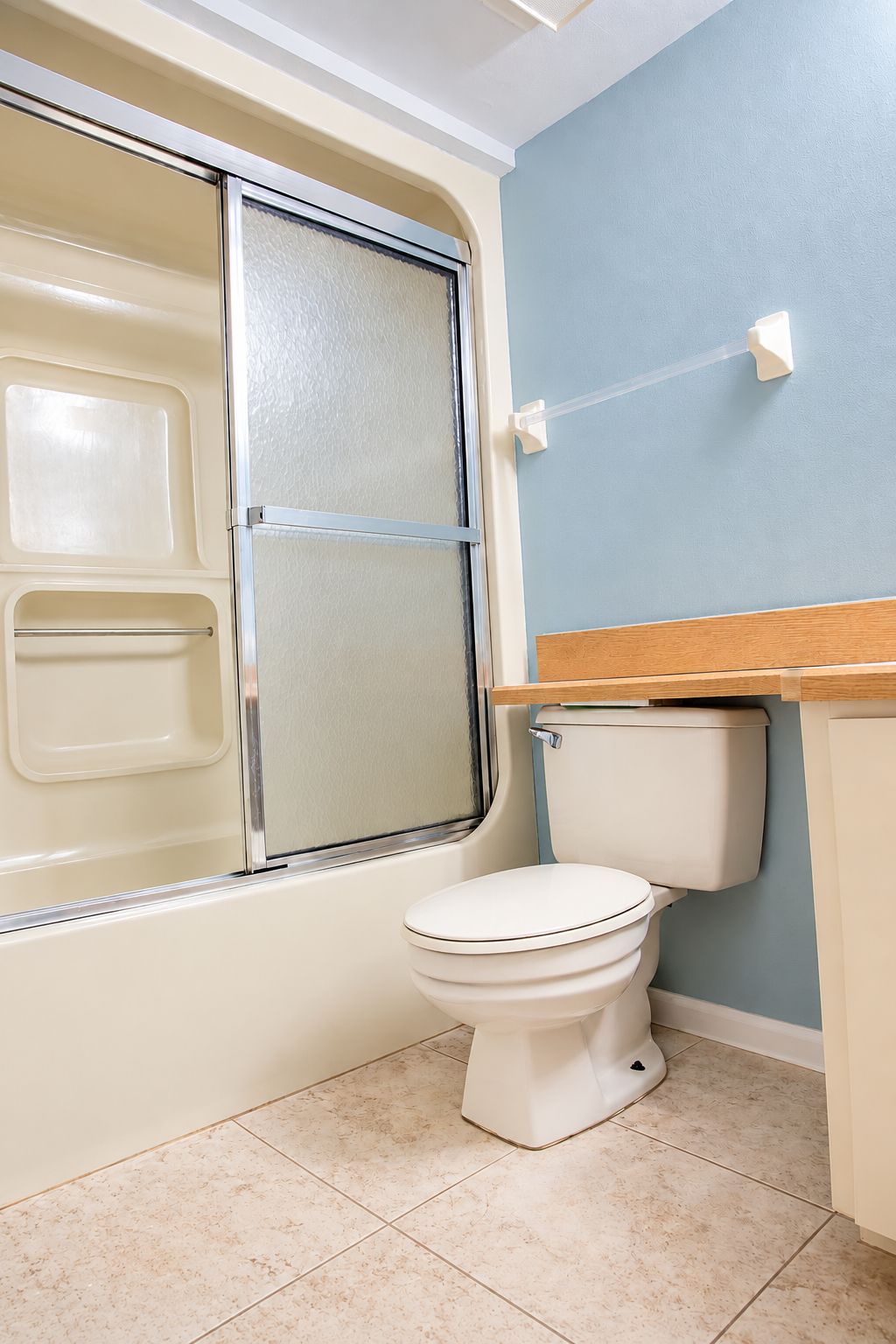 A bathroom with a bathtub, toilet, and a wooden vanity.