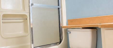 A bathroom with a bathtub, toilet, and a wooden vanity.
