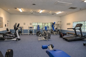 Une salle de sport équipée de divers appareils d’exercice, notamment des tapis de course, des appareils de musculation et un vélo d’appartement.