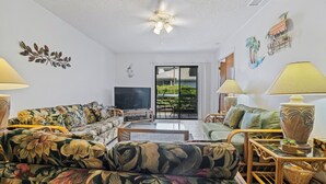 A living room with a sofa, armchairs, a TV, and a ceiling fan. - 250 Sea Woods - 3BD - Your Beach Escape Awaits (New Smyrna Beach)