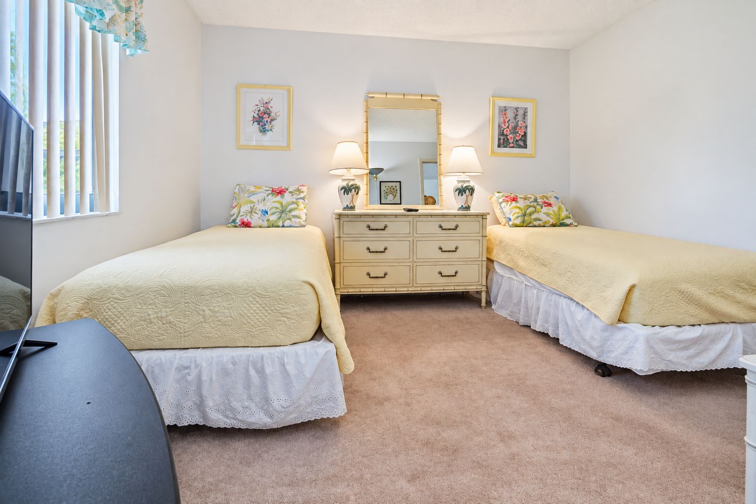 Une chambre avec deux lits, une commode, un miroir et un bureau.