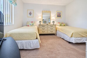 A bedroom with two beds, a dresser, a mirror, and a desk. - 250 Sea Woods - 3BD - Your Beach Escape Awaits (New Smyrna Beach)
