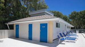 A small building with three blue doors labeled "MEN" and a row of blue lounge chairs outside.