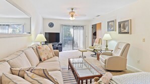 A living room with a sofa, armchair, coffee table, and a television.