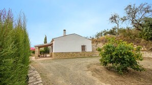 Una casa de un piso con base de piedra y fachada blanca.