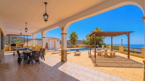 A covered outdoor area with a pool, lounge chairs, and a dining table. - Casa Vistamar Torrox by Ruralidays (Málaga)