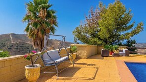 A rooftop terrace with a pool, seating area, and potted plants.