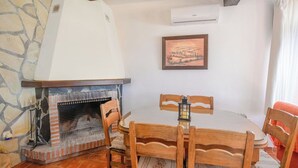 Ein Essbereich mit Kamin aus Ziegelsteinen, Holzsesseln, einem Tisch und einem gerahmten Bild an der Wand.