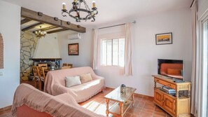 A cozy living room with a sofa, a glass coffee table, a television, and a fireplace. - Casa Vistamar Torrox by Ruralidays (Málaga)