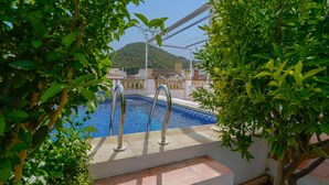 A swimming pool with metal railings, surrounded by greenery and buildings in the background. - Casa Rural Parador del Silo Cónchar by Ruralidays (Granada)
