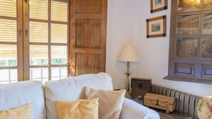 A cozy living room with a white sofa, a wooden bench, and a lamp. - Casa El Rosario Ronda by Ruralidays (Málaga)
