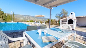 A poolside area with a table, chairs, and a barbecue grill. - Casa El Rosario Ronda by Ruralidays (Málaga)
