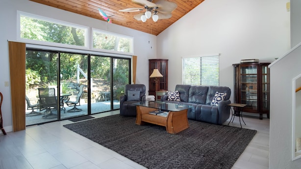 A spacious living room with a large sliding glass door leading to a patio, a ceiling fan, a sofa set, and a coffee table. - 4305 Sea Woods Home 3/3.5 - Stay Salty, Sleep Happy (New Smyrna Beach)