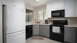 A modern kitchen with white cabinets, a black microwave, a black stove, and a dishwasher. - 4305 Sea Woods Home 3/3.5 - Stay Salty, Sleep Happy (New Smyrna Beach)